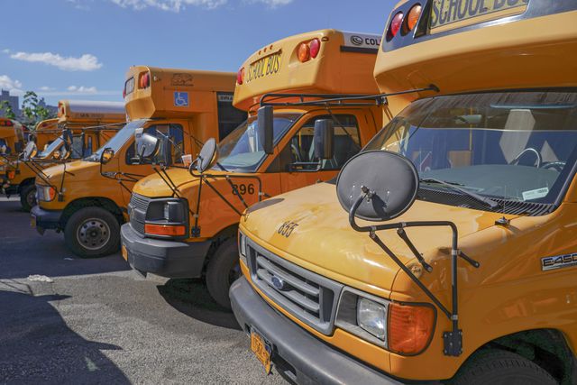 NYC school buses parked in a city lot.